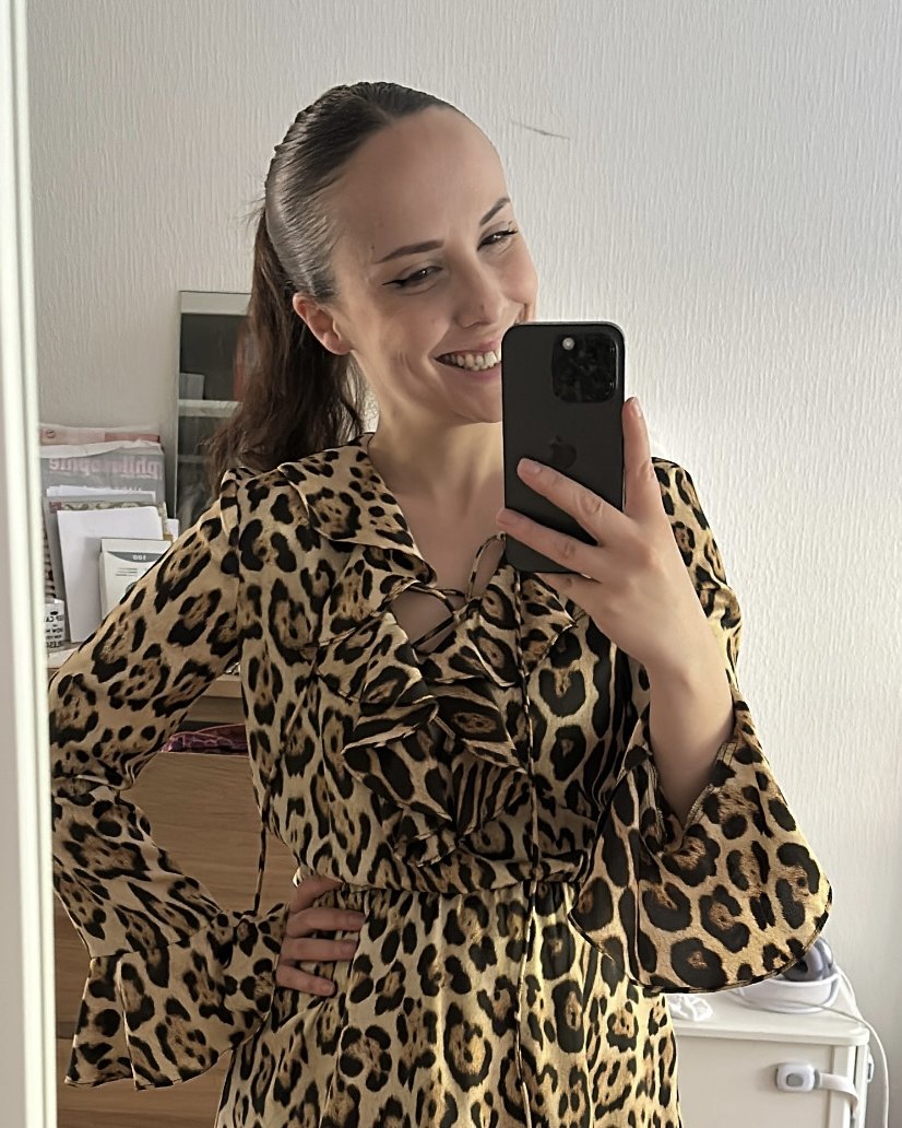 Gabby, souriante, en robe léopard à volants, se prend en photo dans un miroir